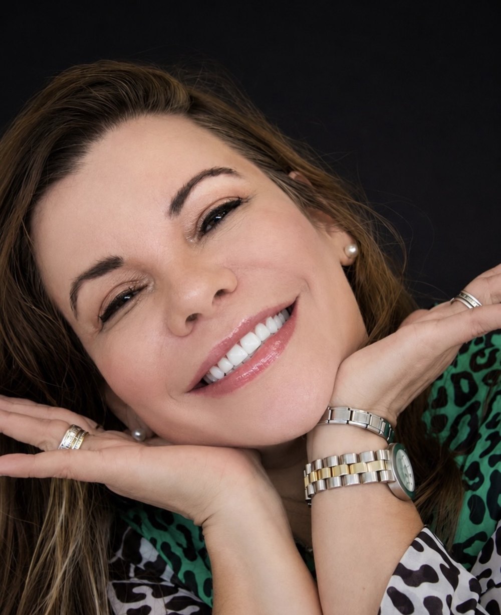 Paciente sorrindo com as mãos no rosto após as facetas em resina